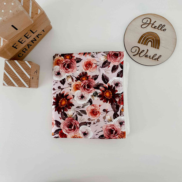 Burp cloth for babies in soft pink floral blithe print placed next to an announcement disk located in Canada