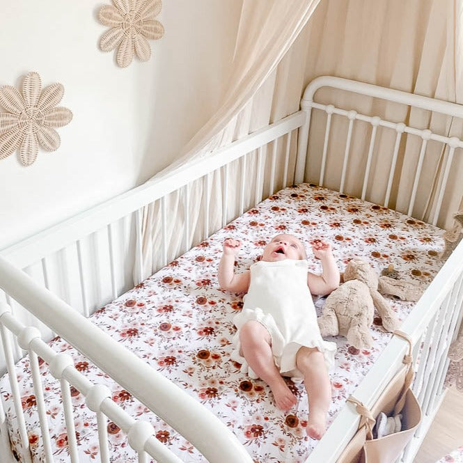 An adorable baby laying beside a stuffed bunny both in a crib using the WIllow fitted sheet from snuggly jacks canada