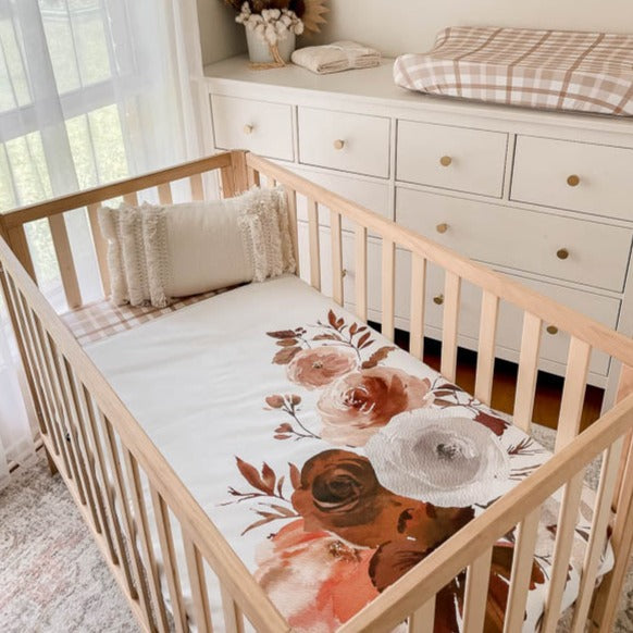 Styled nursery with plaid sheets and change pad cover showcasing the willow large print crib quilt.