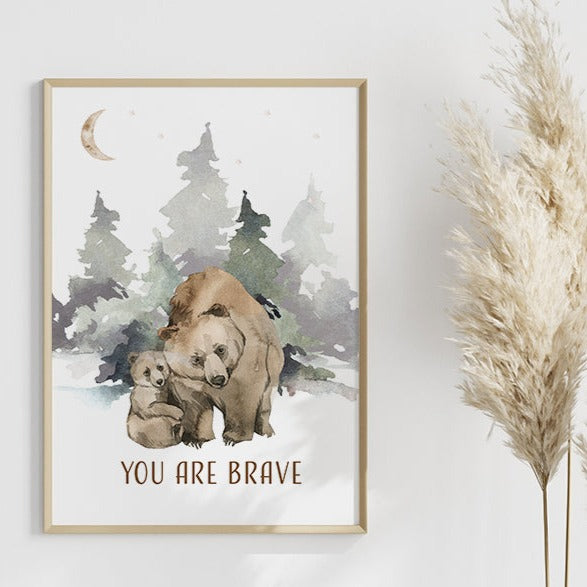 Picture of a brown bear and her cub walking in the forest, in a brown frame hanging on a nursery room wall next to a piece of Pandanus grass